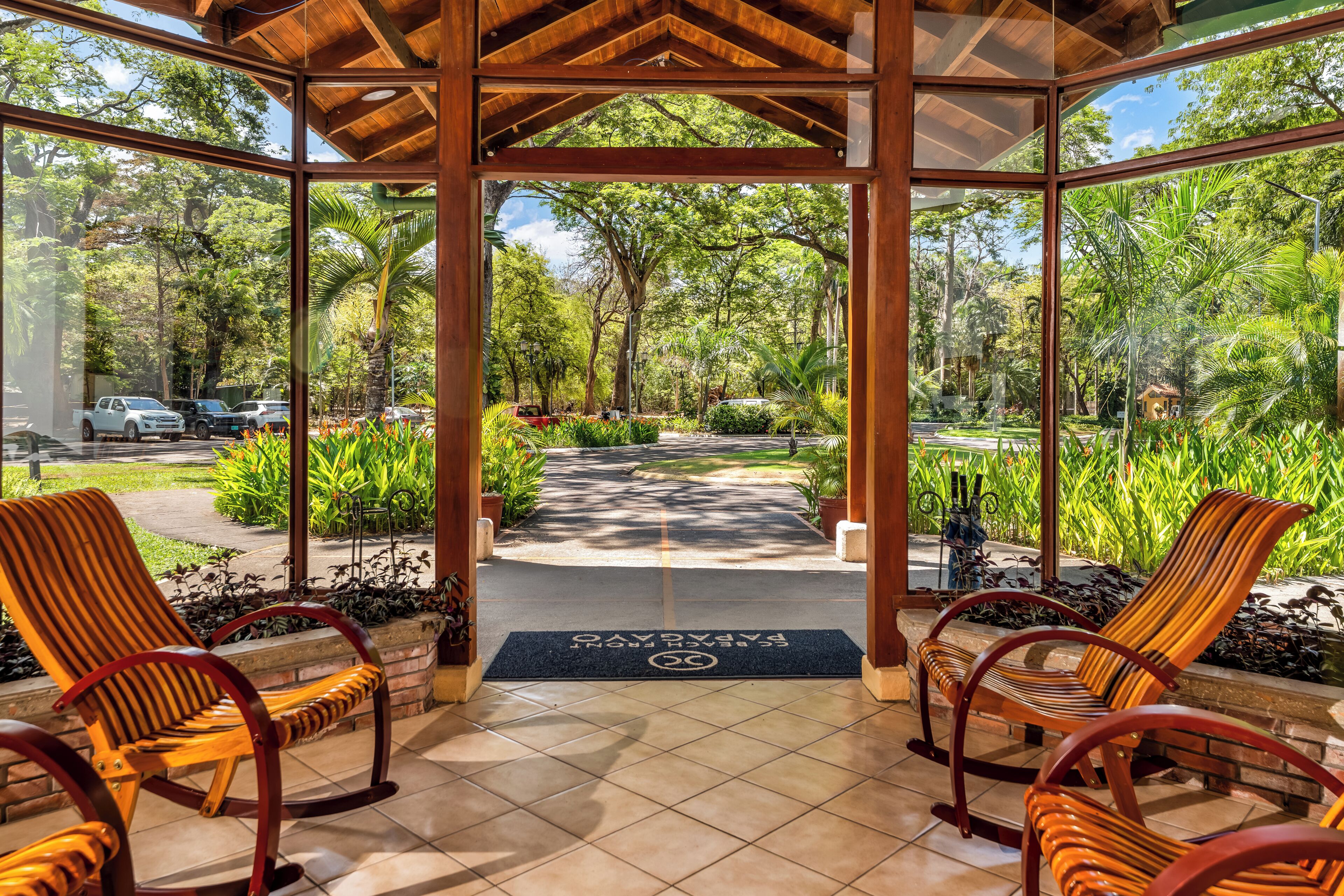 A covered outdoor seating area with chairs and a view of a garden path.