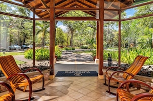 A covered outdoor seating area with chairs and a view of a garden path.