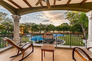A balcony with two rocking chairs, a small table, and a view of a swimming pool and garden. - CC Beach Front Papagayo All Inclusive (Sardinal)
