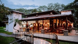 A restaurant with outdoor seating, a covered patio, and a stone pathway leading to the entrance.