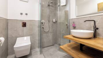 Ein modernes Badezimmer mit einer Glaskabine zur Dusche, einer weißen Toilette und einem Holzausleger mit einem großen Waschbecken.