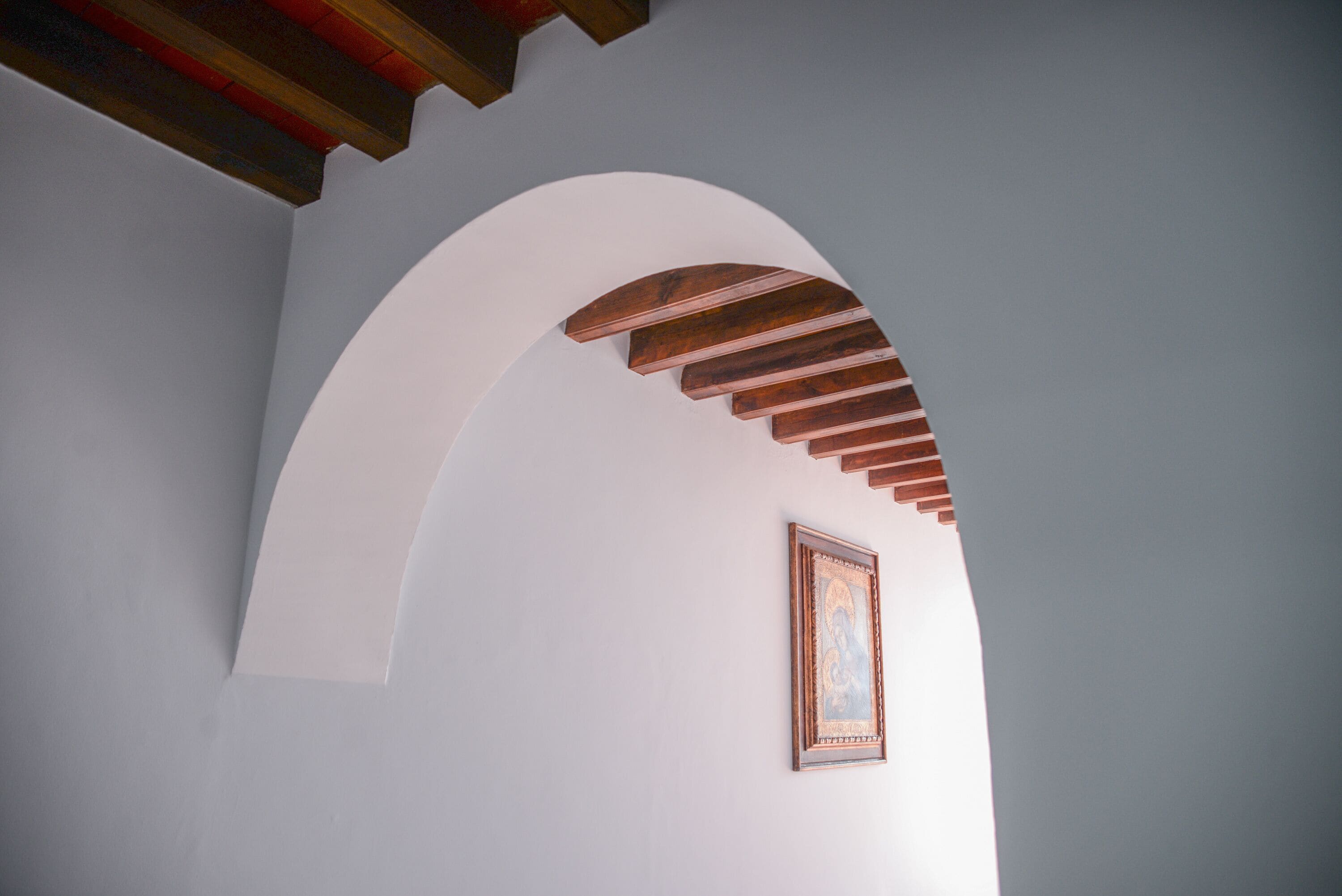 An arched doorway with a wooden ceiling and a framed picture on the wall.