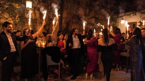 A group of people at an outdoor event with tables and chairs, some holding sparklers. - Hotel De La Parra (Oaxaca)