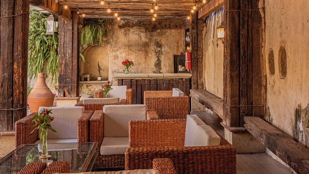 A rustic interior with exposed wooden beams, wicker furniture, and hanging lights. - Hotel De La Parra (Oaxaca)