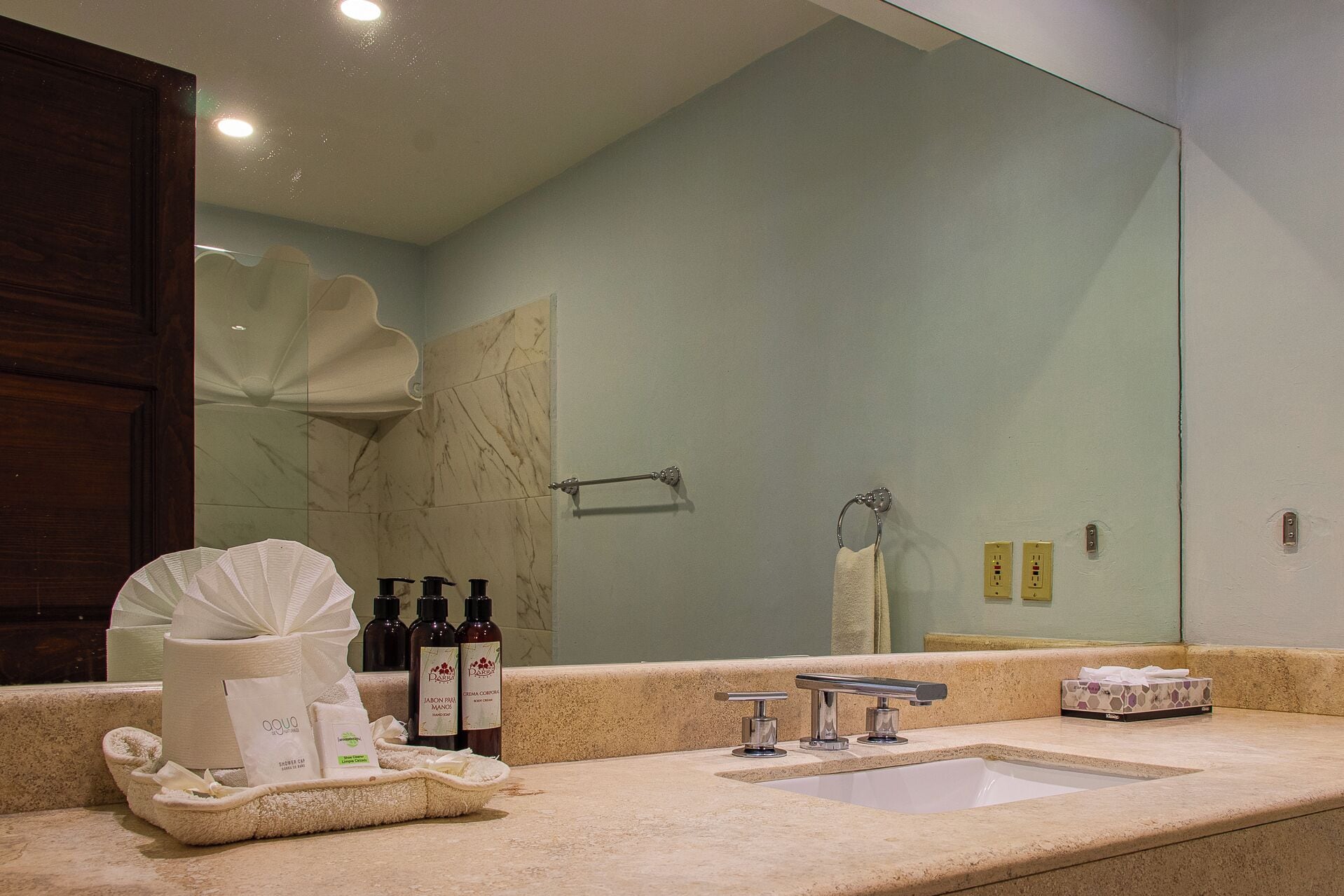 A bathroom with a large mirror, a sink, and toiletries on the counter.