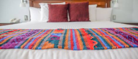 A bed with a colorful blanket, a wooden headboard, and two bedside lamps.
