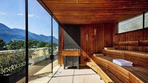 A modern sauna with wooden benches and a glass wall offering a mountain view. - Four Points By Sheraton Panoramahaus Dornbirn (Dornbirn)
