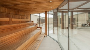 A modern interior with wooden benches and a glass wall offering a view of the outside. - Four Points By Sheraton Panoramahaus Dornbirn (Dornbirn)