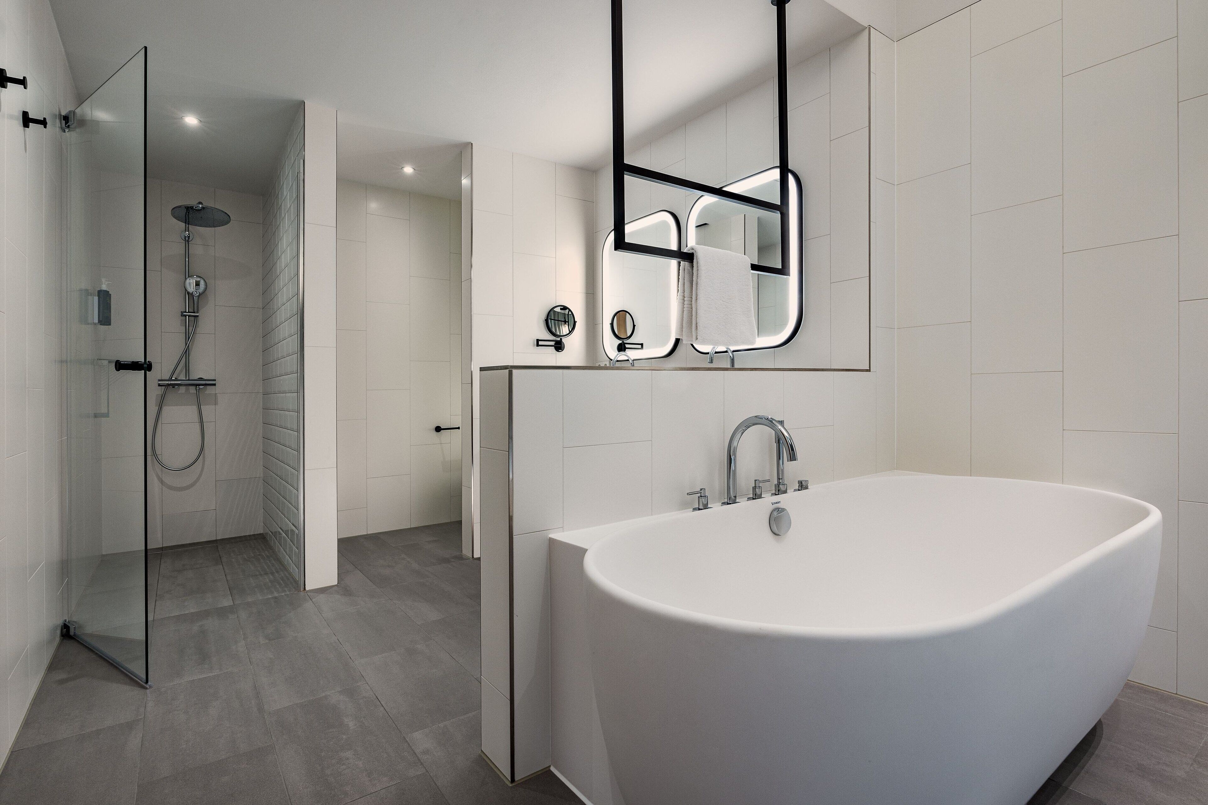 A modern bathroom with a freestanding bathtub, a glass shower enclosure, and a large mirror.