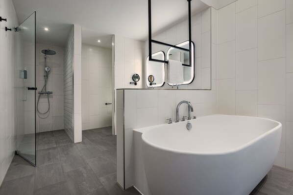 A modern bathroom with a freestanding bathtub, a glass shower enclosure, and a large mirror.
