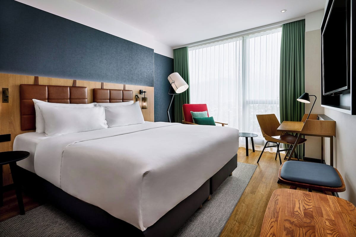 Une chambre d’hôtel avec un grand lit, un bureau, une chaise et un téléviseur.