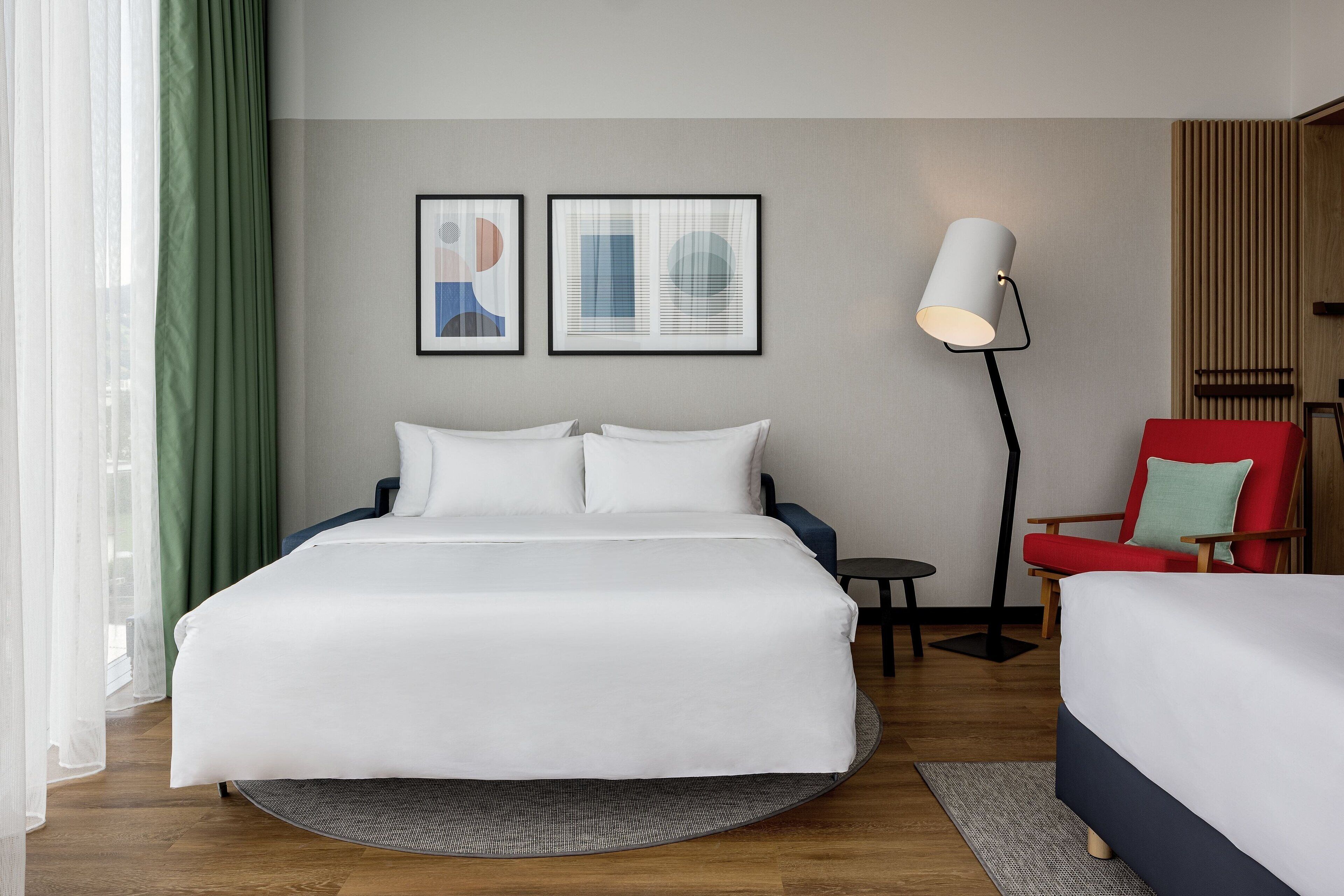 Habitación de hotel con una cama grande, un escritorio, una silla y dos cuadros en la pared.