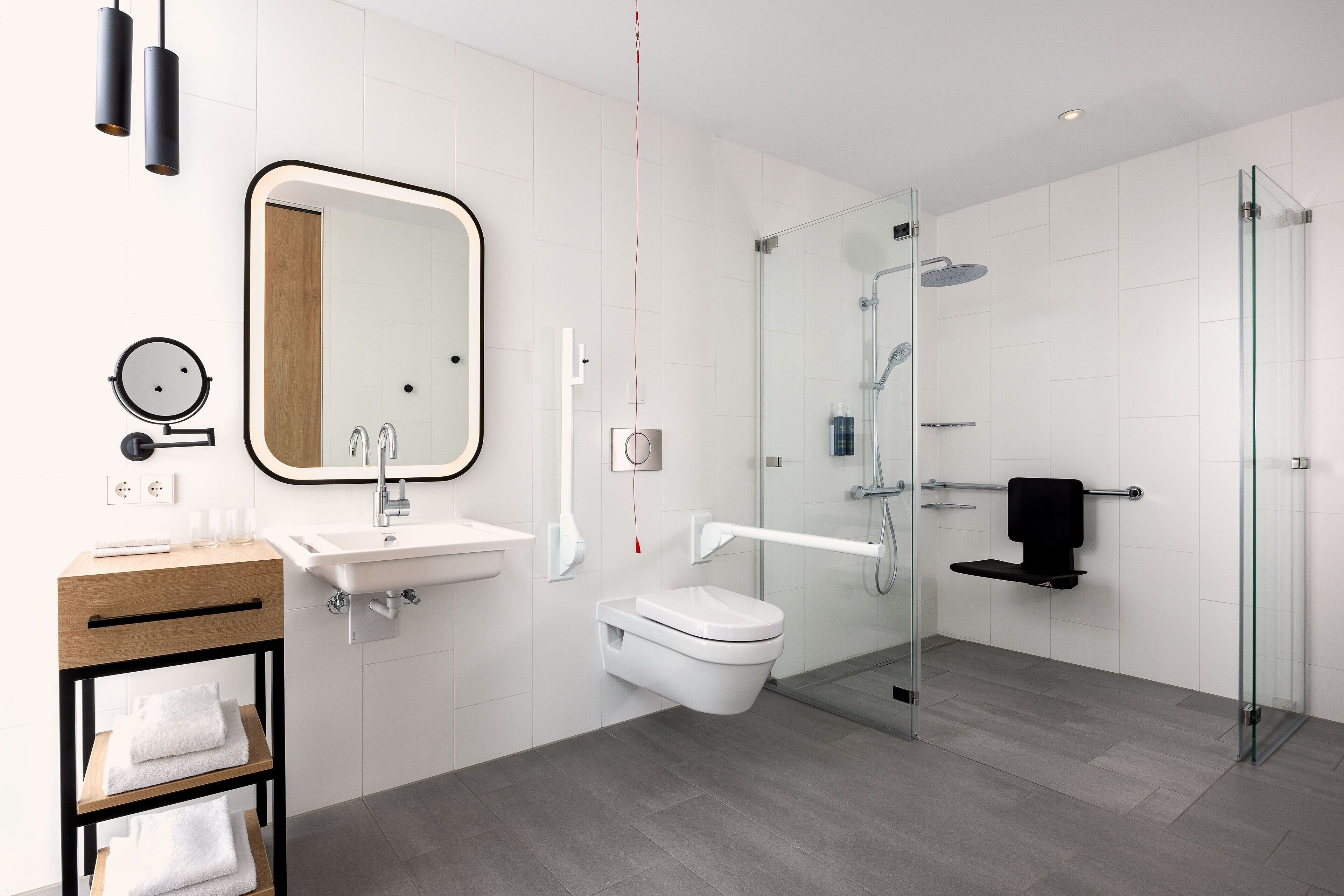 A modern bathroom with a glass shower enclosure, a wooden vanity with a mirror, and a white sink.