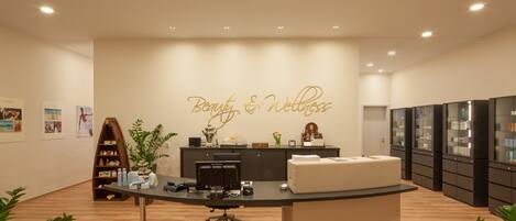 A modern office with a reception desk, a large wall sign reading "Beauty & Wellness," and a display of products.