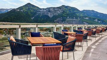 Una terraza con mesas y sillas, con vistas a un paisaje montañoso.