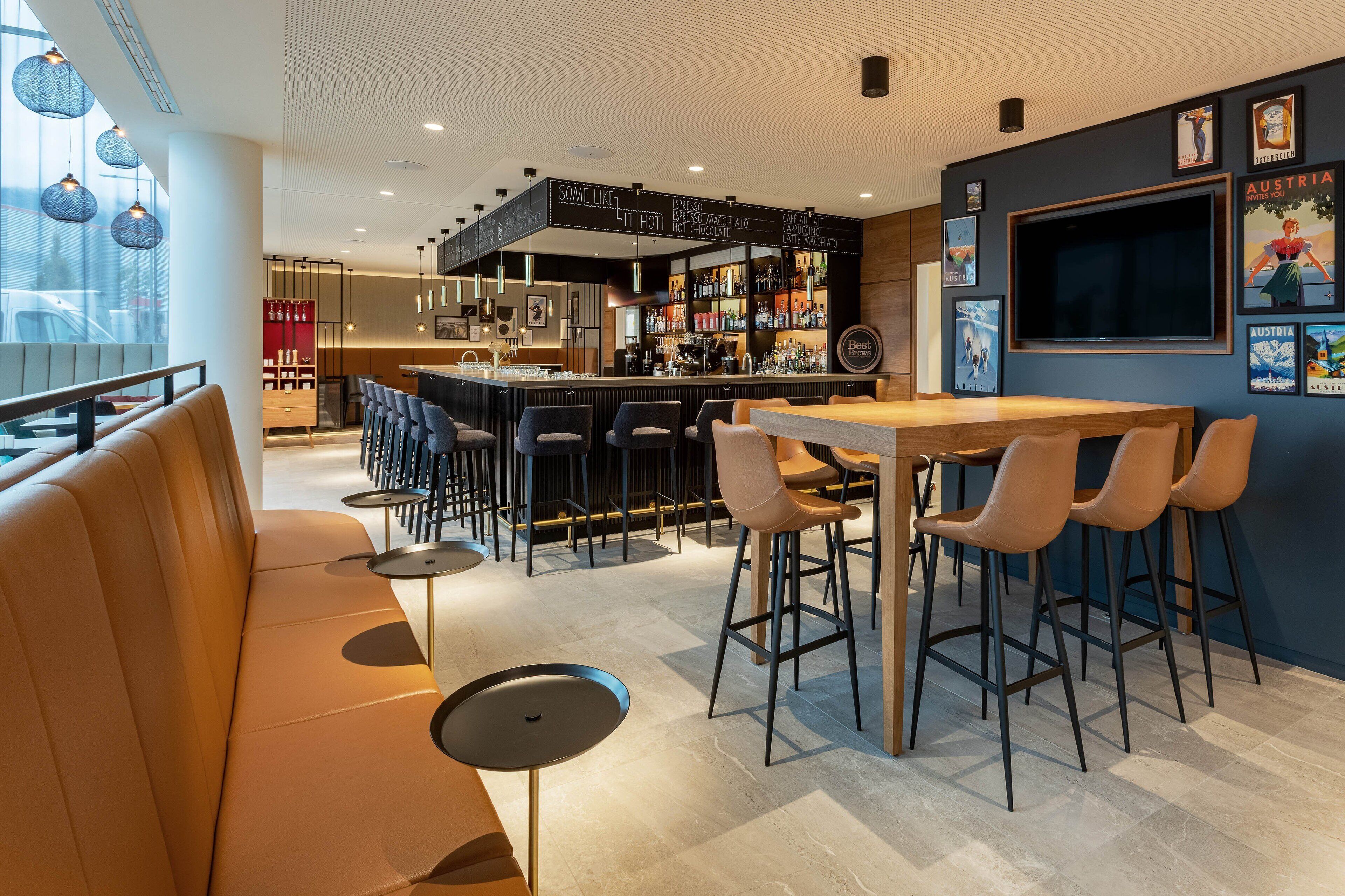 Eine moderne Bar mit einer Theke, Barhocker und einer Lounge mit Sofa und Tischen.
