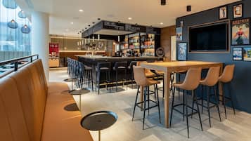 Eine moderne Bar mit einer Theke, Barhocker und einer Lounge mit Sofa und Tischen.