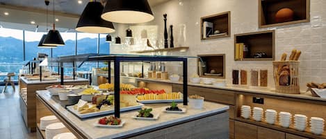 Ein reichhaltiges Buffet mit verschiedenen Speisen und Blick auf die Berge im Hintergrund.