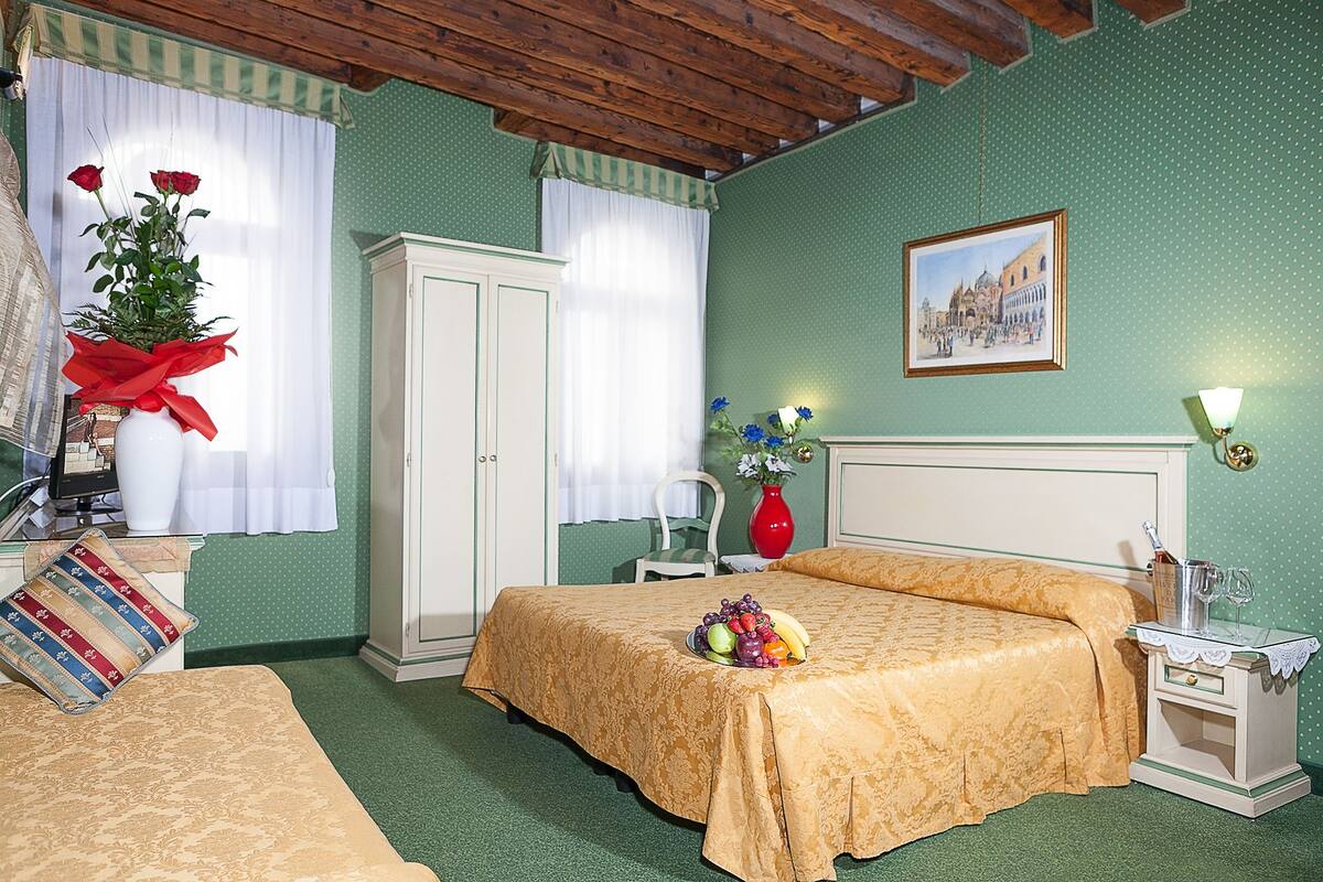 A bedroom with a bed, a nightstand, a dresser, a chair, and a window with curtains.