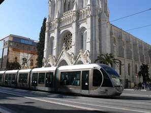 Un tramway moderne passe devant une cathédrale historique, remarquable pour ses détails architecturaux complexes et sa grande rosace.