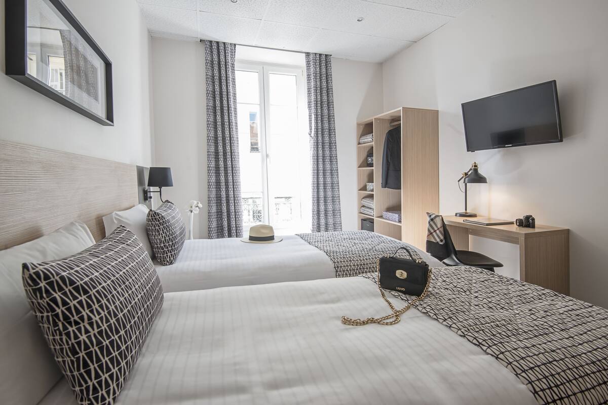Una habitación de hotel con dos camas, televisión, escritorio y armario.