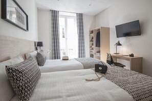 Une chambre d’hôtel avec deux lits, un bureau, une télévision et une armoire.