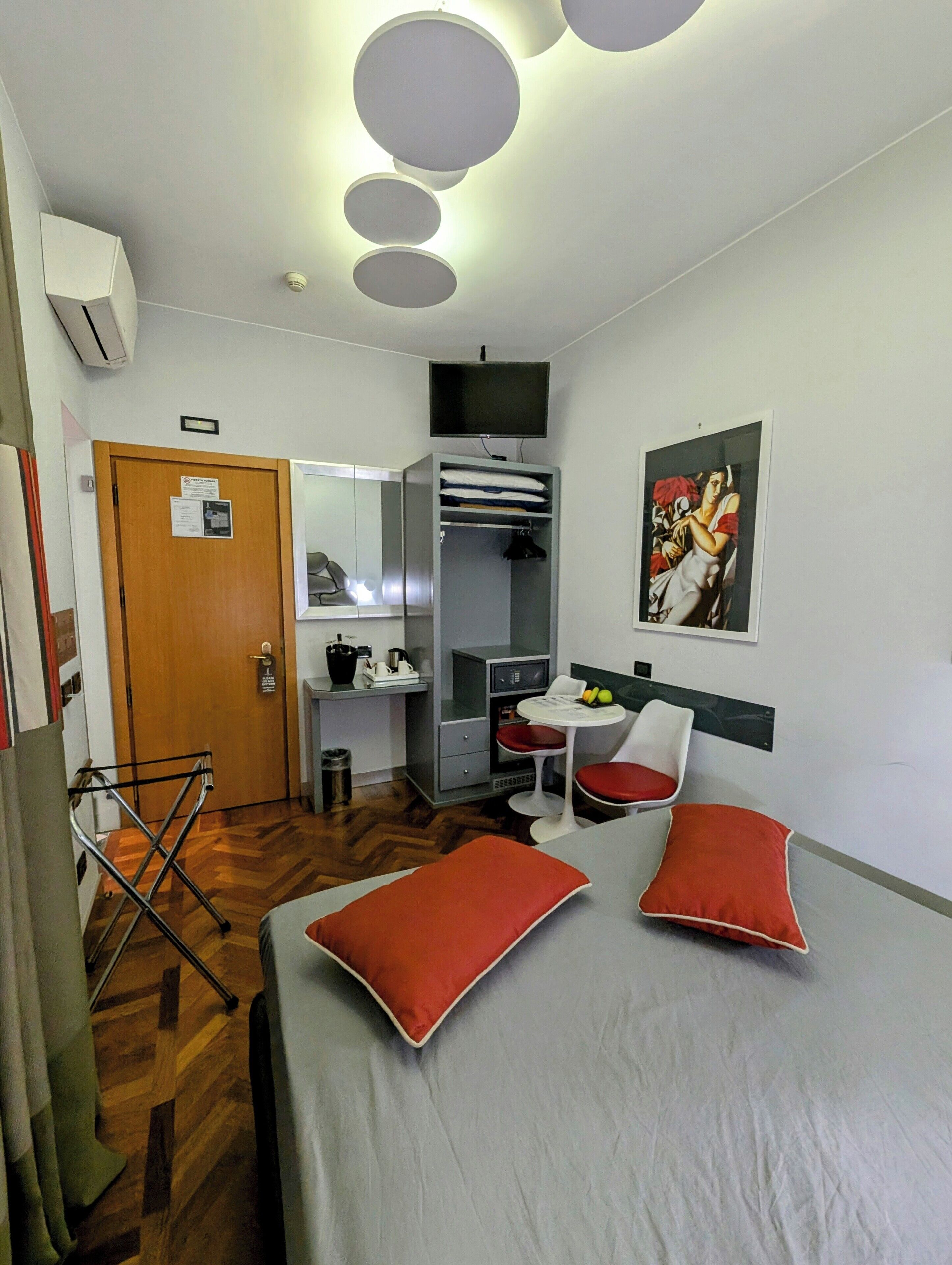 Una camera d'albergo con un letto, una scrivania, una sedia, un armadio e un televisore.