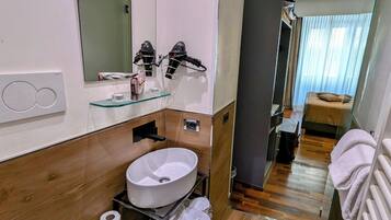 Un bagno moderno con uno specchio grande, un lavandino rotondo e un water.