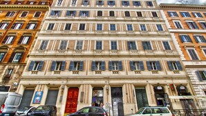 A multi-story building with a classical facade, featuring evenly spaced windows and a central entrance with a red door. - Relais Forus Inn (Rome)