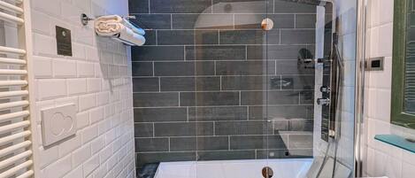 A modern bathroom with a white toilet, a bathtub, and a glass-enclosed shower.