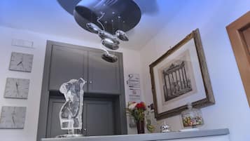 Una stanza con un lampadario moderno, una scultura in vetro decorativa, un quadro incorniciato e orologi alle pareti.