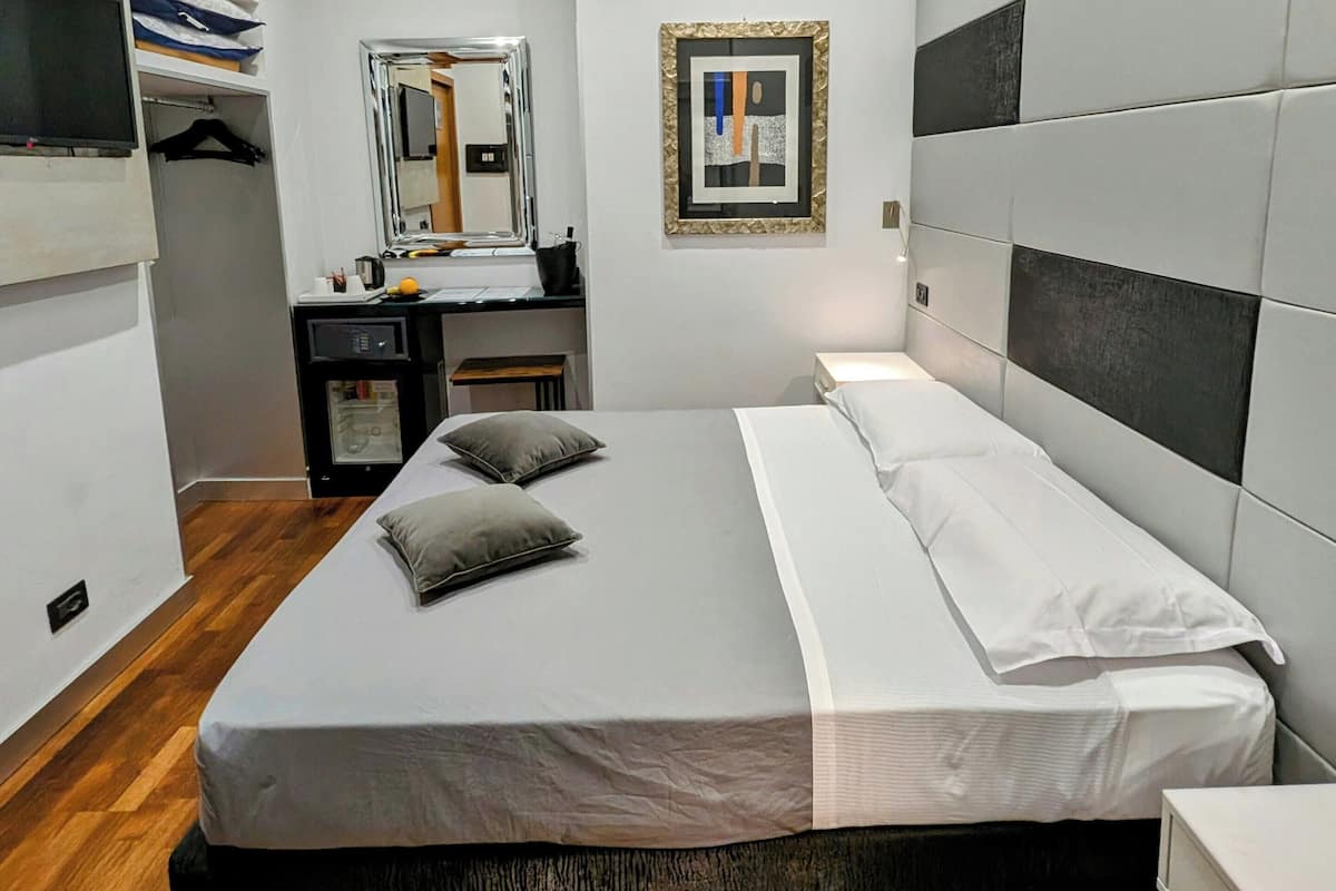 A modern bedroom with a bed, bedside table, and a mirror.