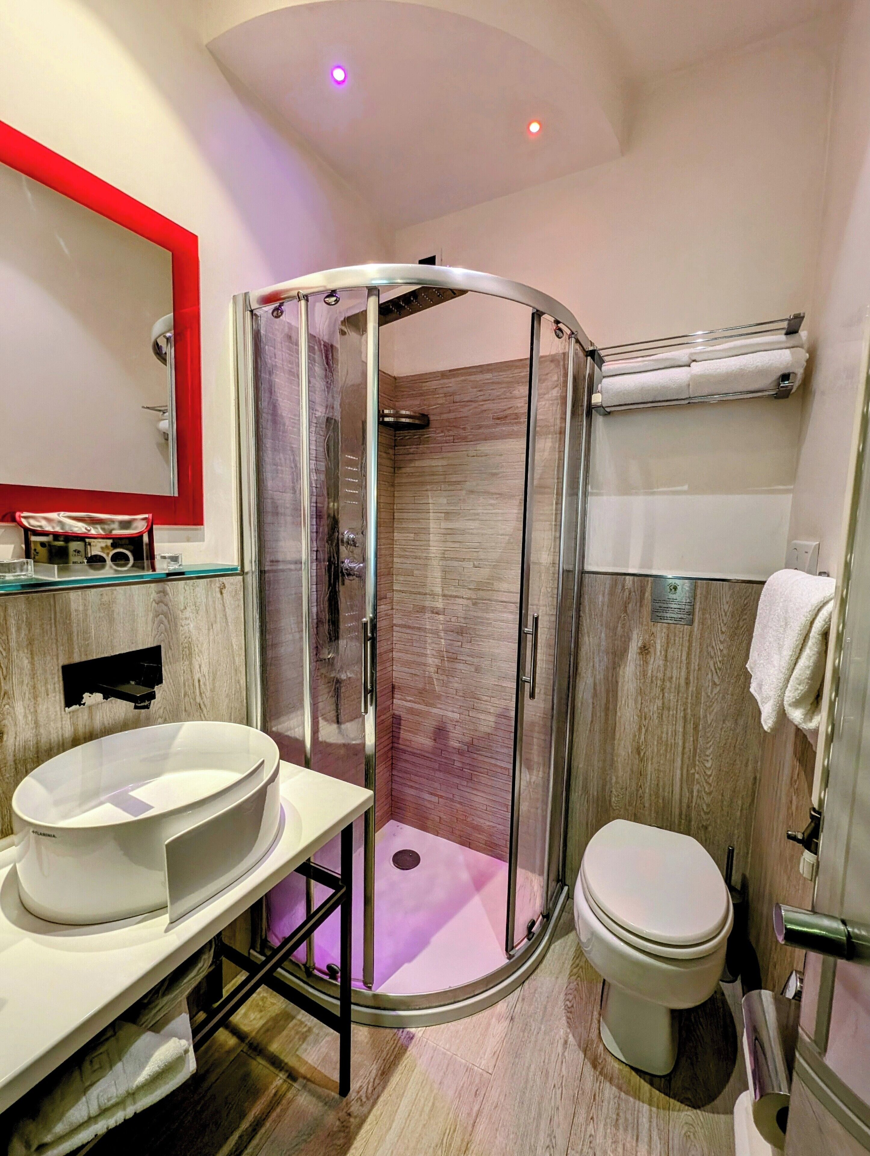 A modern bathroom with a glass-enclosed shower, a white sink, and a toilet.
