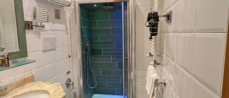 A bathroom with a shower, toilet, sink, and towel rack.