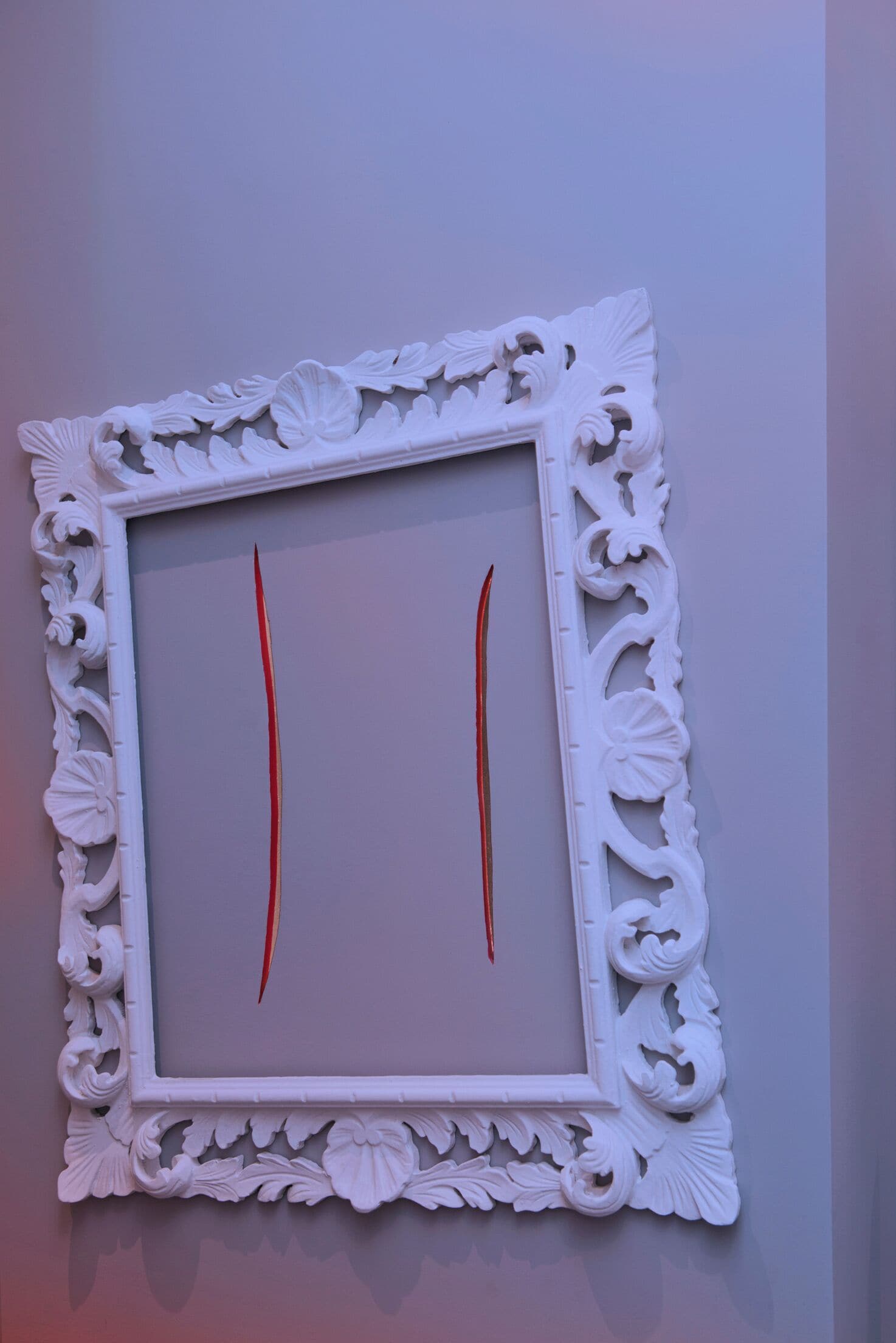 A white ornate picture frame with two red lines in the center.