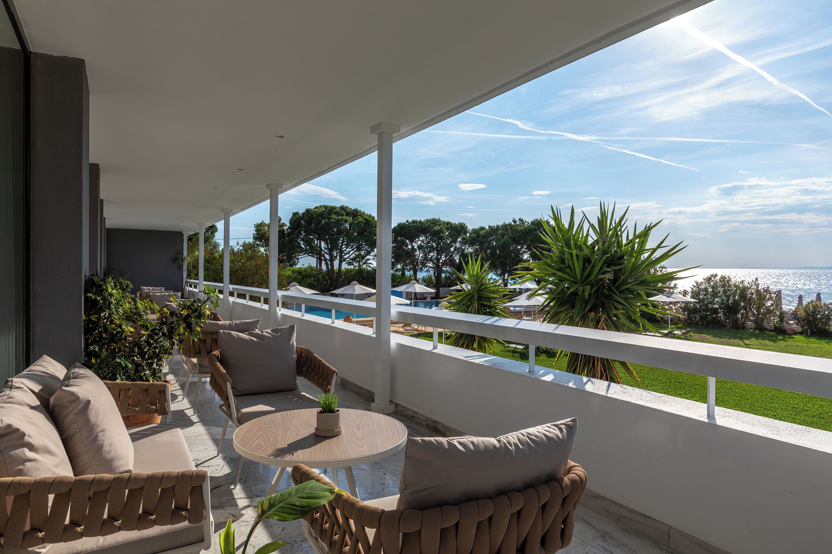 Un balcon avec vue sur la mer, des meubles d’extérieur et des plantes en pot.