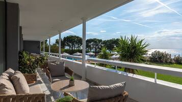 Un balcon avec vue sur la mer, des meubles d’extérieur et des plantes en pot.