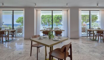 Un restaurante con amplios ventanales, suelo de mármol y mobiliario de madera.
