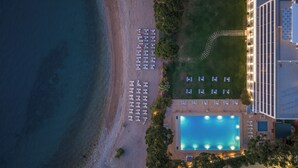 An aerial view of a hotel with a swimming pool, beachside lounge chairs, and a well-maintained lawn. - Airotel Achaia Beach (Patras)