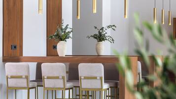 Un intérieur moderne avec un espace bar, des sièges et des luminaires suspendus.