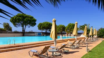 Una piscina al aire libre de temporada, sombrillas