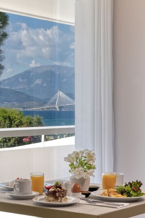 A breakfast table with a view of a bridge and mountains.