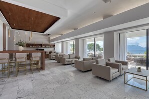 Amplia sala de estar con bar, asientos y ventanas grandes con vista al mar.
