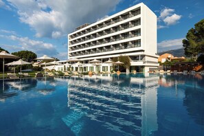 Un hotel con piscina, varios balcones y zonas de estar al aire libre.