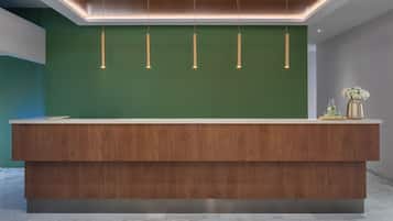 A reception desk with a green wall, wooden paneling, and pendant lighting.