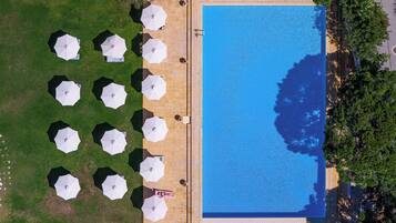 Vista aérea de una piscina rodeada de sombrillas y un césped.