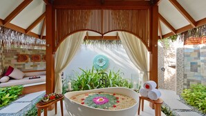 A spa area with a large bathtub, a wooden bench, and a small table with towels.