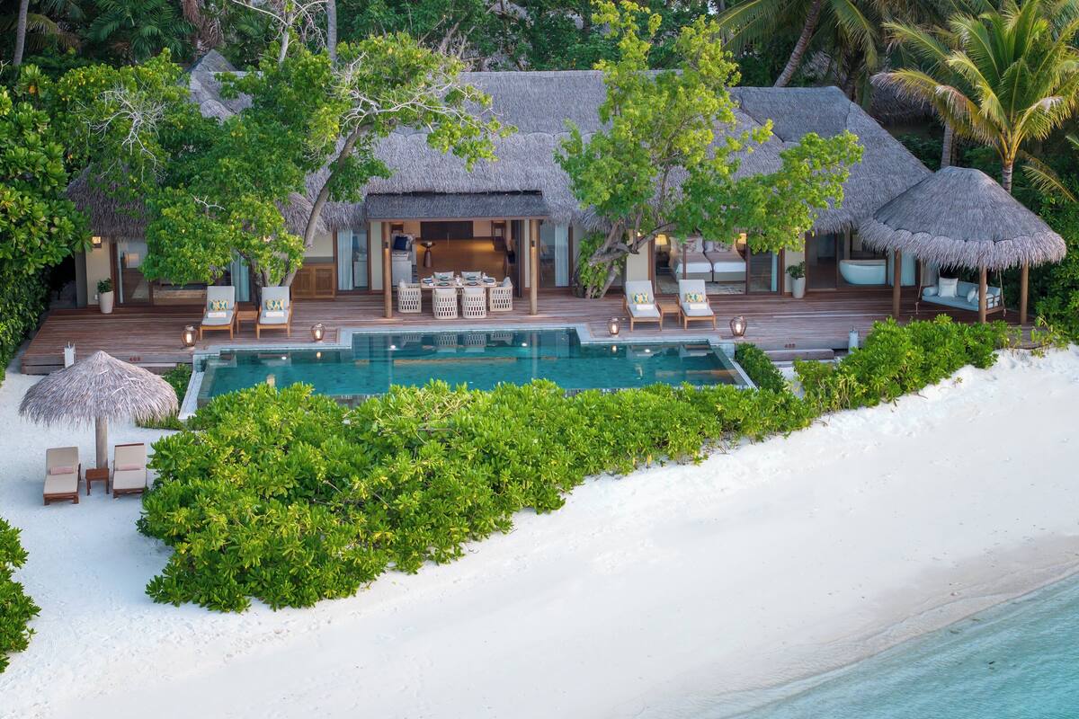 A resort with a pool, lounge chairs, and thatched-roof structures.