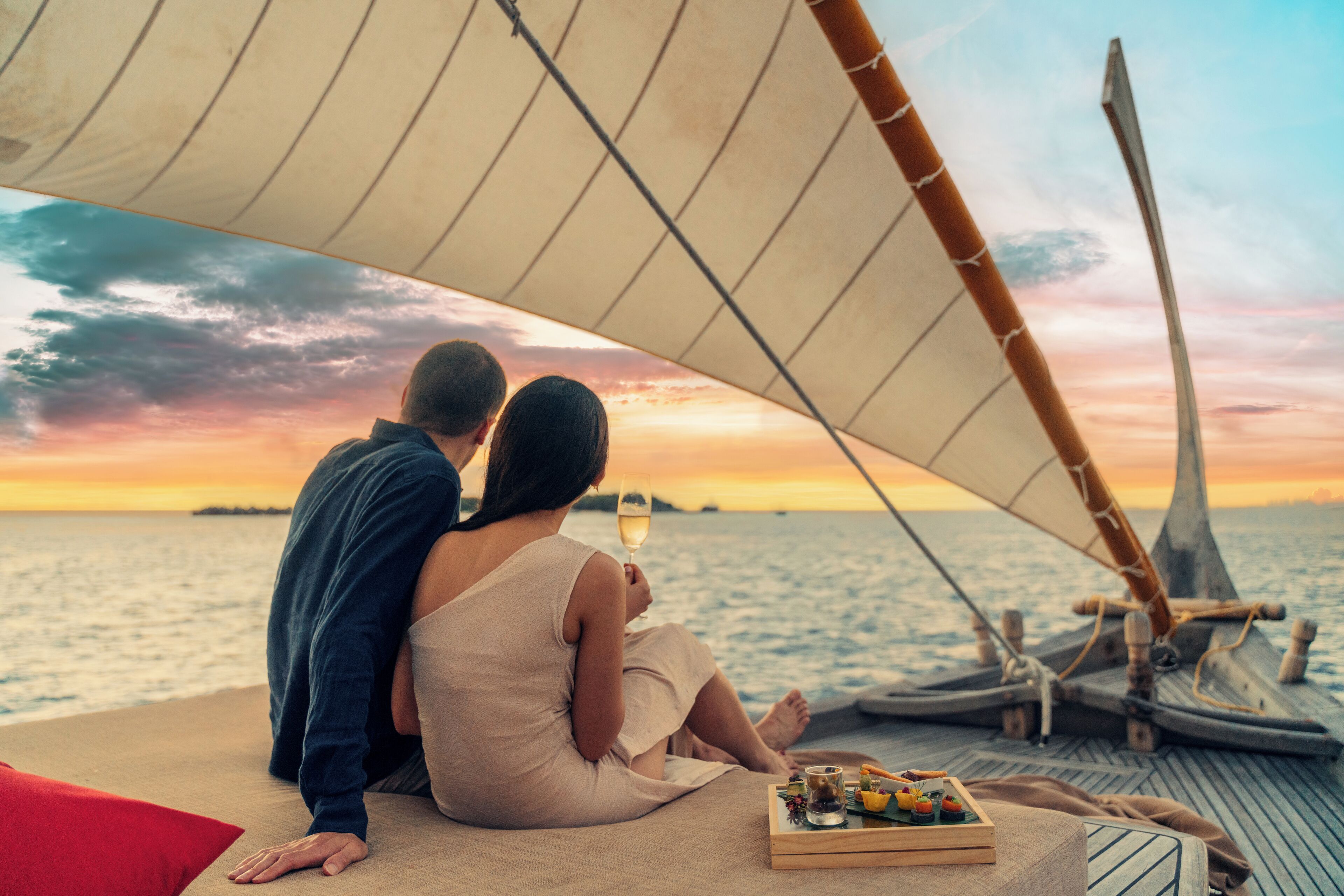 A couple on a sailboat with a sunset view.