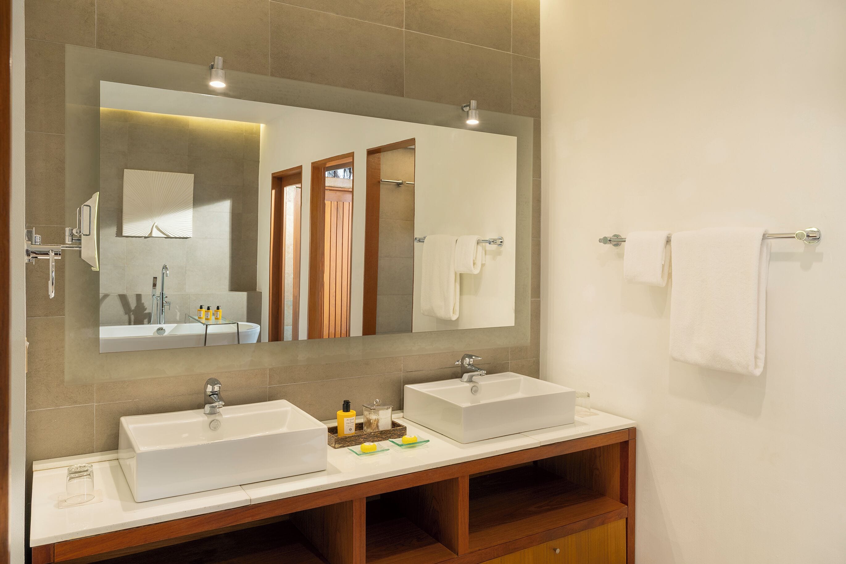 A modern bathroom with two sinks, a large mirror, and a wooden vanity.